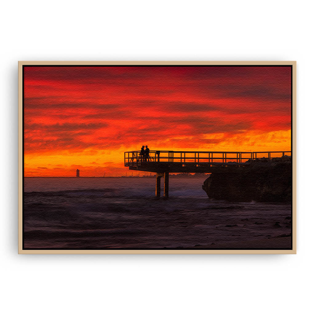 Couple watch sunset from the end of jetty in North Beach, Western Australia framed canvas in raw oak