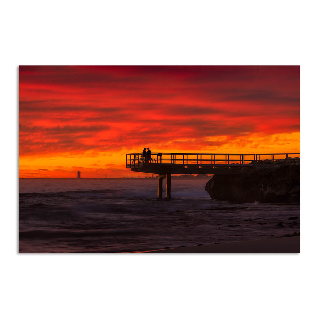 Couple watch sunset from the end of jetty in North Beach, Western Australia