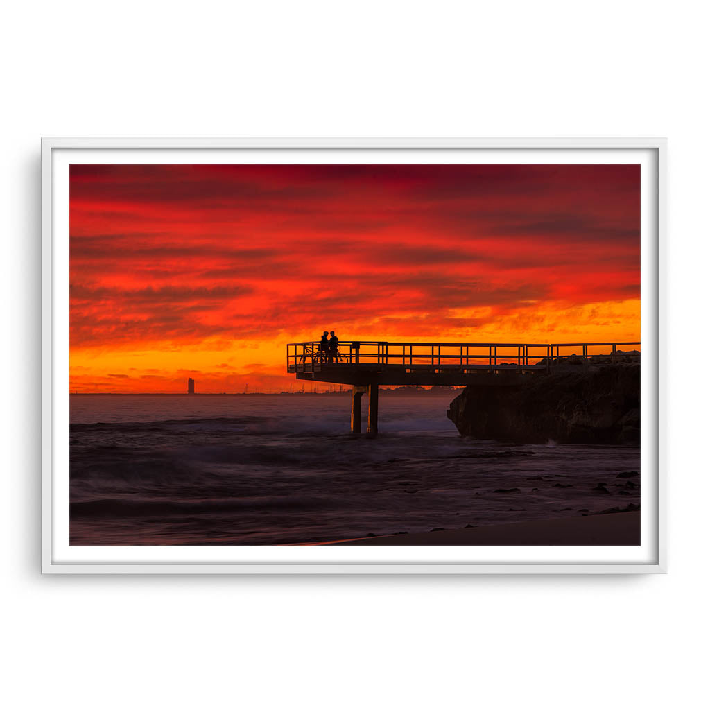 Couple watch sunset from the end of jetty in North Beach, Western Australia framed in white