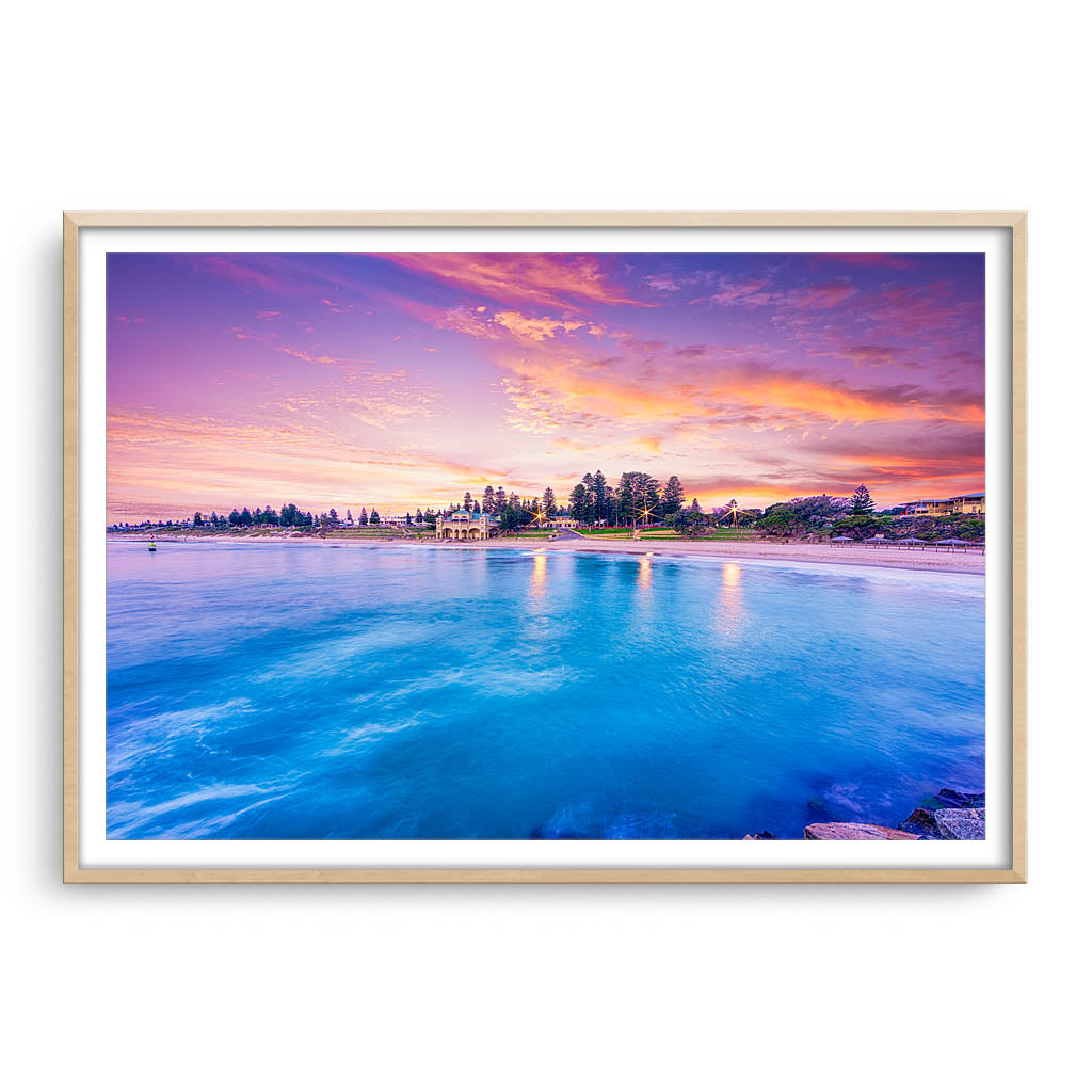 Blue waters and magenta skies over Cottesloe in Perth, Western Australia framed in raw oak